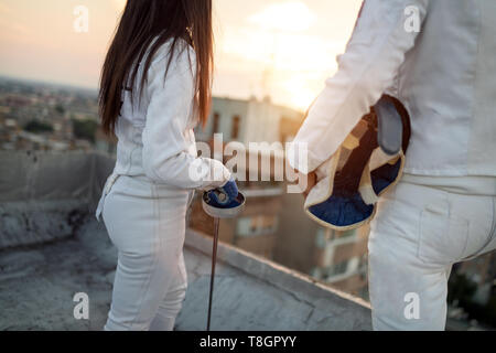 Two fencing athletes people fight on rooftop outdoors Stock Photo