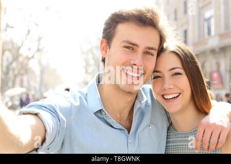 Happy couple are taking selfies in the street on summer holiday in a big city Stock Photo