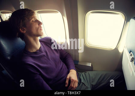 young man sleeping in an airplane seat. traveler in an plane Stock Photo