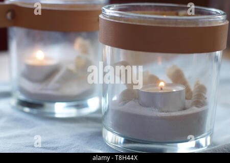Two glasses with burning candles on the table, gently blue gamma Stock Photo