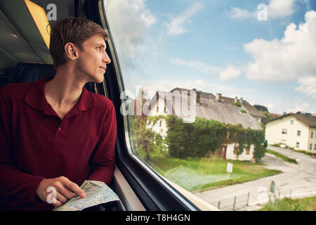 handsome young man using a map on the train. traveler on the road Stock Photo