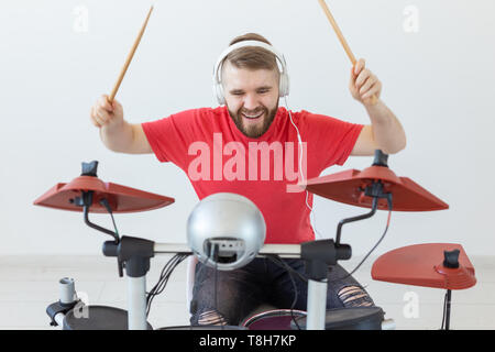 People, music and hobby concept - Man dressed in red t-shirt playing on the electronic drum set Stock Photo