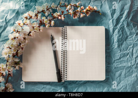 Open blank notebook, pen and cherry blossoming branch on bright background. Concepts of romance and love Stock Photo