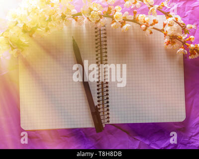 Open blank notebook, pen and cherry blossoming branch on bright background. Concepts of romance and love Stock Photo