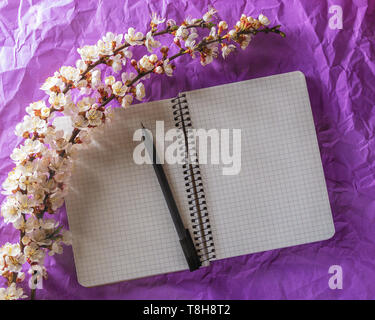 Open blank notebook, pen and cherry blossoming branch on bright background. Concepts of romance and love Stock Photo