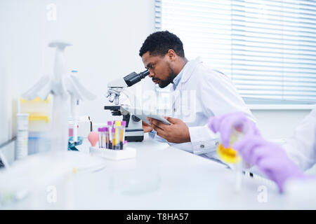 Concentrated lab technician using microscope Stock Photo
