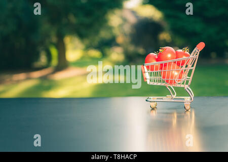 A miniature shopping cart full of tomatoes. Stock Photo