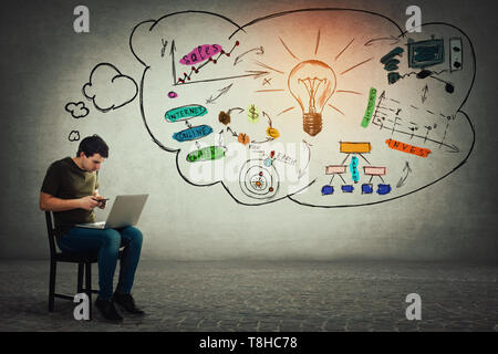 Freelancer sitting on chair using his laptop and mobile phone at a time, making different calculations and planning future. Positive thinking, idea co Stock Photo