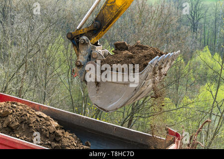 Working excavator shovel. Dump truck detail with soil pile. Building machine. Hydraulic digger bucket pouring dirt on lorry. Earth mover. Excavation. Stock Photo