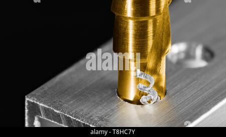 Step drill bit. Twisted swarf detail. Making hole in aluminum profile. Unibit closeup. Drilling of aluminium alloy by cutting tool coated by titanium. Stock Photo