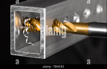 Spiral fluted steel tap bit making a thread in hole of alu profile ...