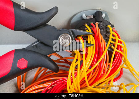 Diagonal cutting pliers detail. Parallel cables, mechanic rotary switch. Wire cutters. Dismantled old electronic device. Colored tangle cords. E-waste. Stock Photo