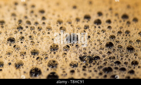 Coffee surface texture. Foam bubbles in detail. Aromatic hot drink. Abstract frothy background. Mirroring in bubbly brown fluid. Beverage with caffein. Stock Photo