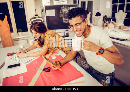 Joyful tailors working in a studio and laughing. Stock Photo