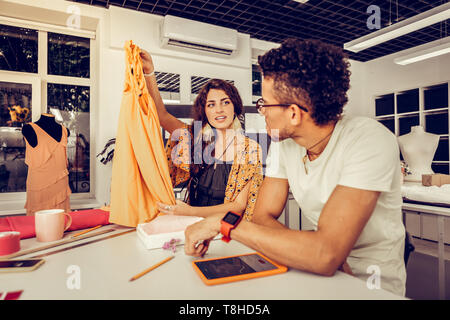 Designer showing a new dress to her colleague. Stock Photo