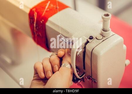Hand of a tailoress inserting thread into the sewing machine. Stock Photo