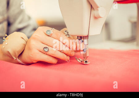 Hand of a designer in a process of sewing a dress. Stock Photo