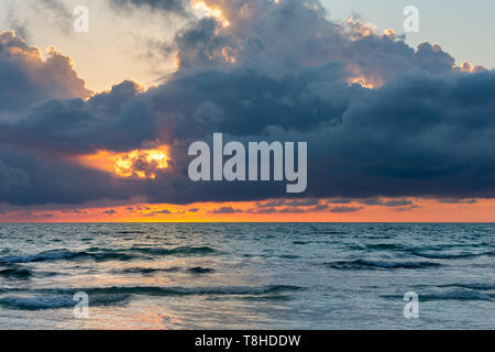 Ocean sunset or sunrise background with dramatic storm clouds and orange reflections on the water. Stock Photo