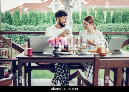 Serious spouses discussing work during breakfast in the garden Stock Photo