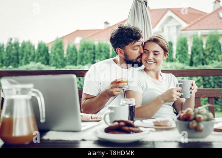 Attractive husband kissing his wife during breakfast in the garden Stock Photo