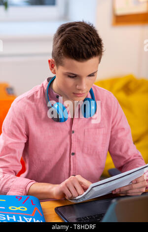 Close up of student wearing earphones on neck doing math homework Stock Photo