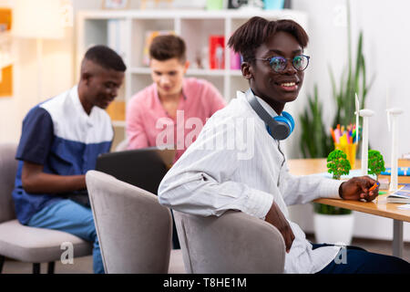 Dark-skinned student wearing glasses sitting at the table Stock Photo