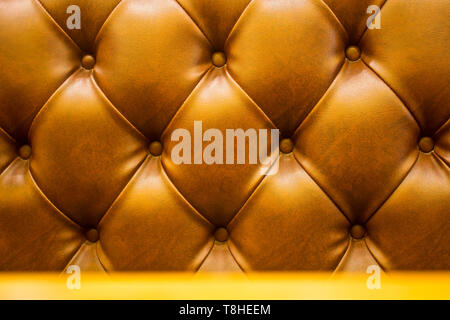 The brown soft leatherette background with asymmetrical buttons. Soft and expensive furniture elements. Luxury background Stock Photo