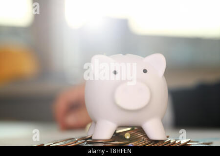 Hand businessman putting pin money into pig Stock Photo
