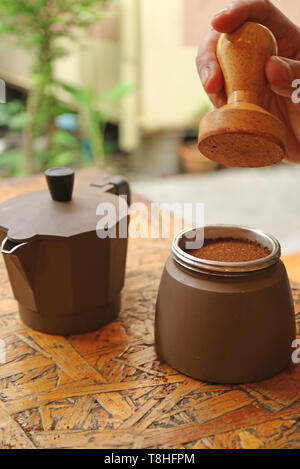Man's Hand Holding Tamper to Tap Ground Coffee for a Flat Surface before Brewing in the Pot Stock Photo