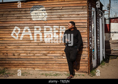 Amos Mgodini standing in front of his barber shop called Ayas in Wallacedene, Cape Town, South Africa. Stock Photo