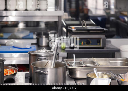 Utensils on metal rack in commercial kitchen Stock Photo - Alamy