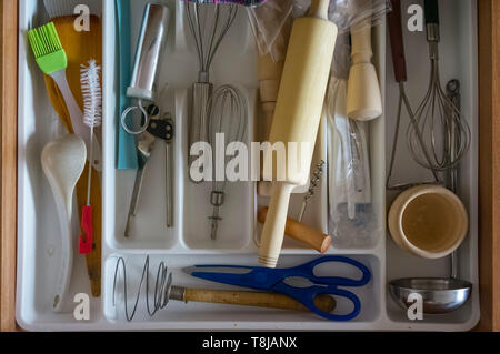 Top view of kitchen organizer with utensils and tools: beaters, blue scissors, silicone green brush, ladle, wooden rolling pin, wooden pestle, wooden  Stock Photo