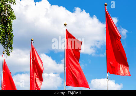Red flags fluttering in the wind against the sky Stock Photo
