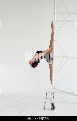 The splits in the air on metal poles.Gymnast in black tights. Flexibility Stock Photo