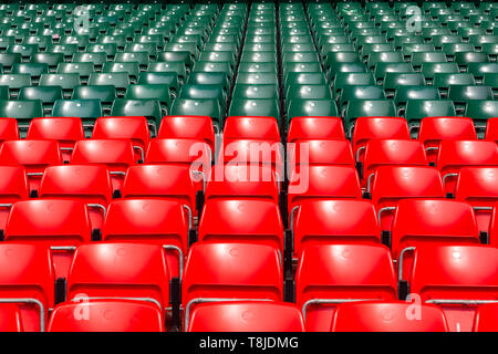 Red and green plastic seats in an empty, large sports stadium Stock Photo