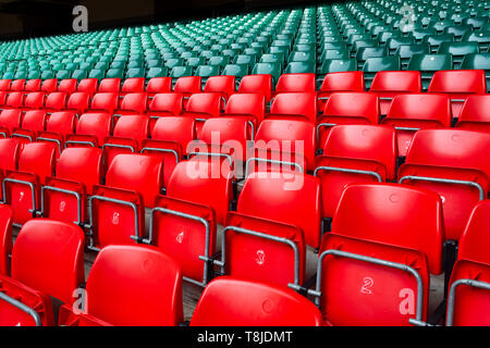 Red and green plastic seats in an empty, large sports stadium Stock Photo