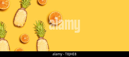 Juicy tropical fruits on a yellow background: oranges, coconuts, lemons, pineapples. Stock Photo
