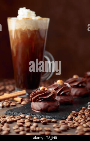 Chocolate dessert with hazelnut and coffee with cream on a wooden table.Coffee beans and cinnamon sticks are scattered on the table. Stock Photo