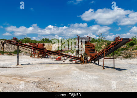 Old rusty stone crushing machines in abandoned quarry Stock Photo