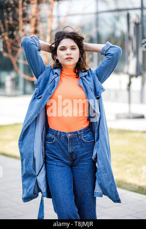 Young pretty girl walking on the street, dressed in jeans and denim shirt Stock Photo