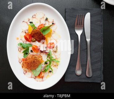 Octopus carpaccio in plate on restaurant table Stock Photo