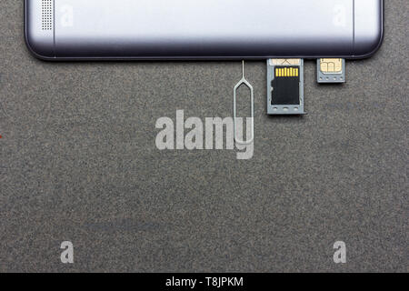 smartphone with open slots with SIM cards and micro SD memory on gray background with copy space, top view close-up Stock Photo