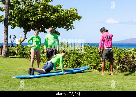 A mother and father look on as their son takes a surfing lesson from a local pro in Hawaii, USA. Stock Photo