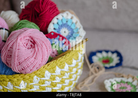Multicolored plaid squares of crocheted on a cream colored seat background Stock Photo