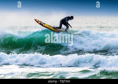 A surfer riding a longboard on the crest of a wave at Fistral in Newquay in Cornwall. Stock Photo