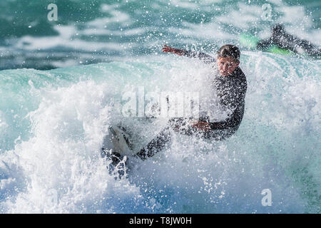 Spectacular surfing action as a young female surfer is covered in spray as she rides a wave at Fistral in Newquay in Cornwall. Stock Photo