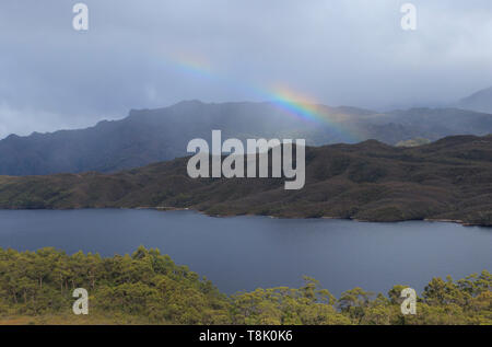 Rainbow over Lake Pedder in South West Tasmania Wilderness as dark rain clouds clear. Stock Photo