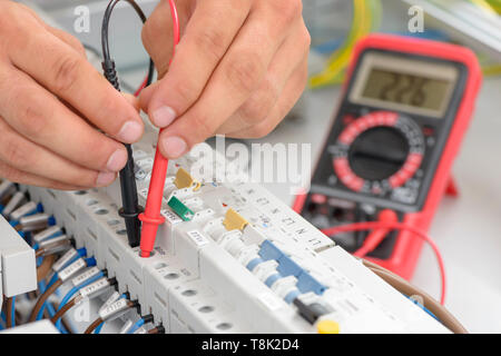 Electrician testing an electric smart panel fuse box, using a multimeter tester Stock Photo