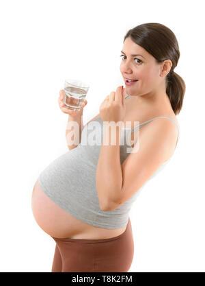 Beautiful smiling pregnant woman taking a pill isolated on white Stock Photo