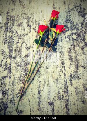 three long red roses in the marble background with old toned effect Stock Photo